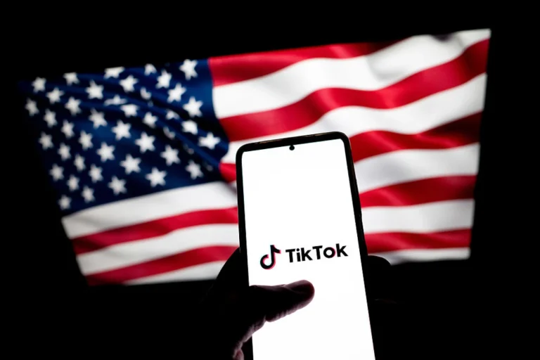 Foto de um celular com o logo do TikTok em frente à bandeira dos Estados Unidos