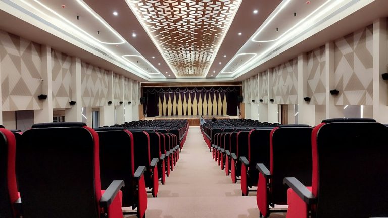 Auditório com poltronas vermelhas e palco, imagem ilustrativa de solenidade de diplomação eleitoral