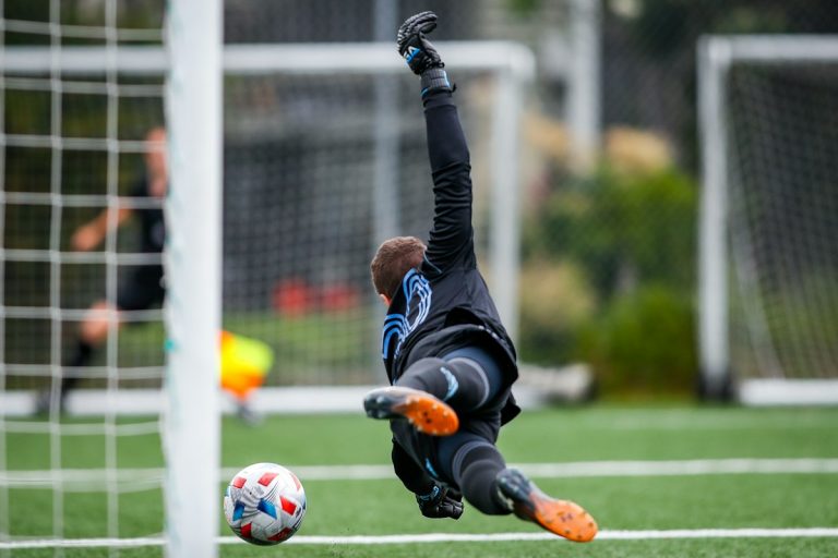 Goleiro salta para realizar defesa em partida de futebol, imagem ilustrativa de My Profit Tutor via Unsplash